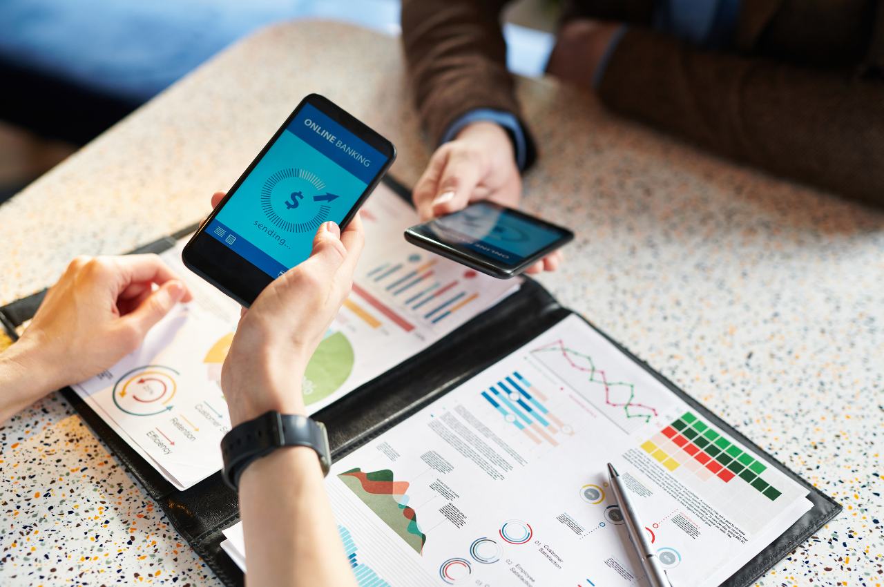 fintech disruptions in financial landscape - people transfering money through phones while looking at financial documents